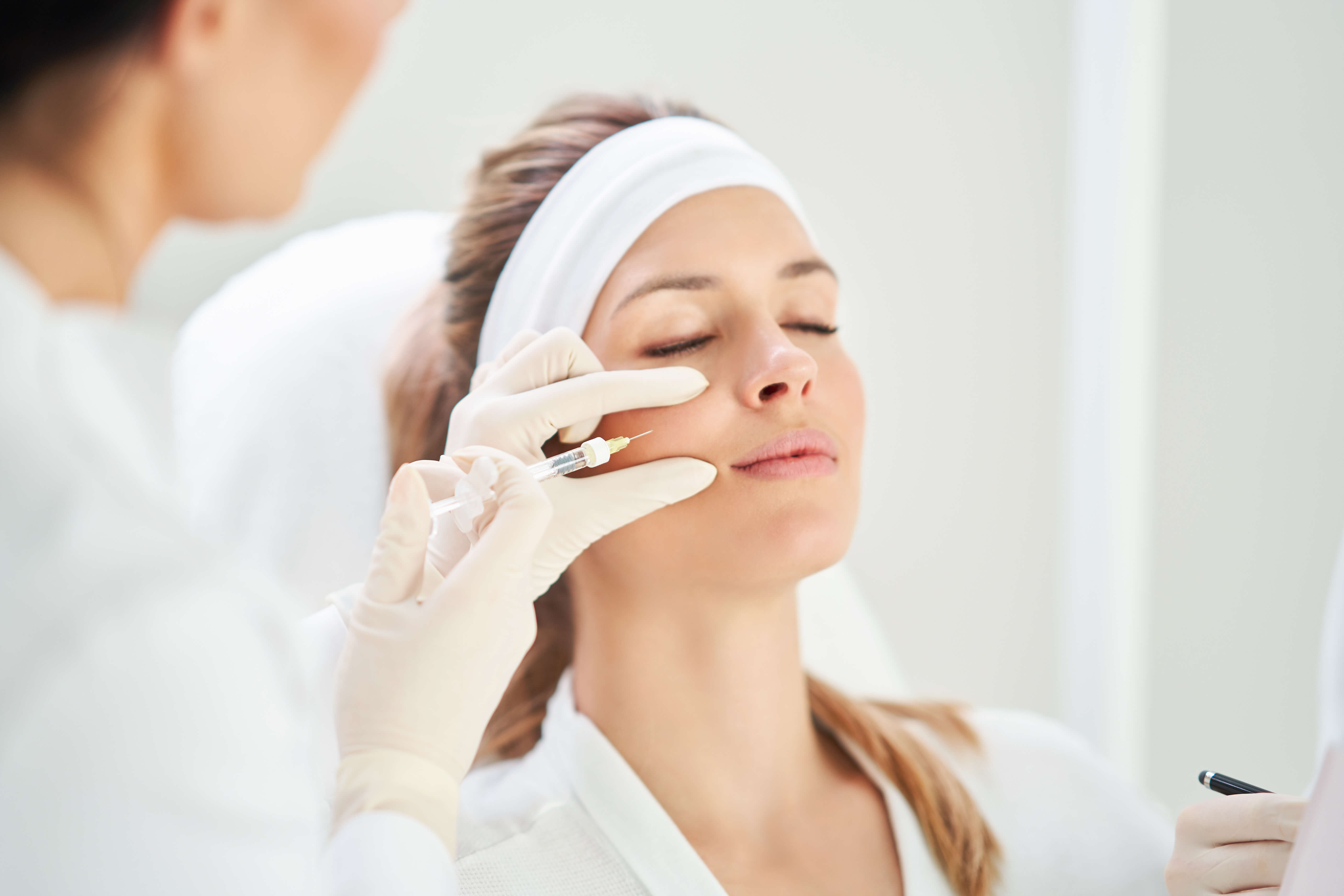 Woman receiving a facial treatment from a professional in a clinical setting.