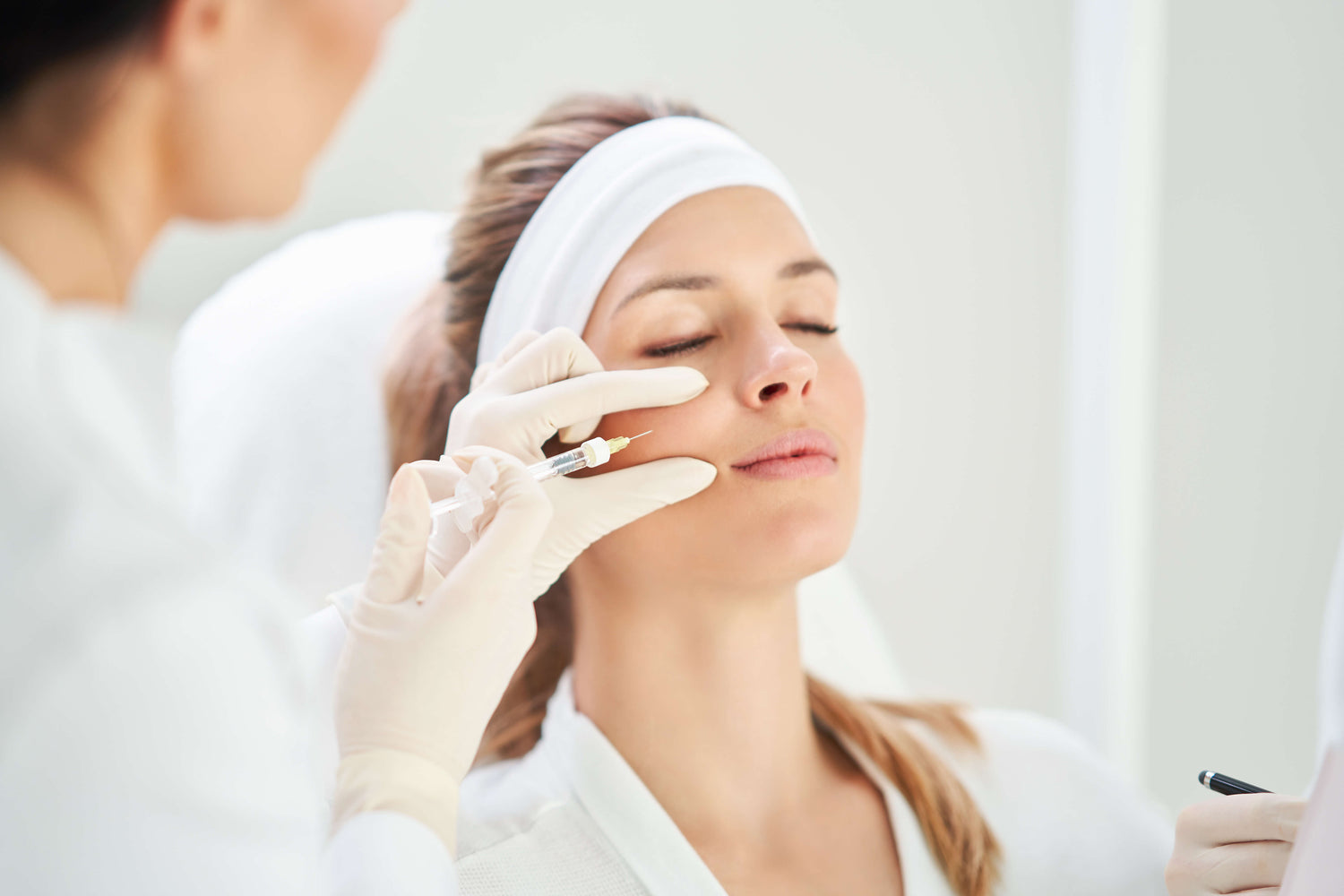 Woman receiving a facial treatment from a professional in a clinical setting.