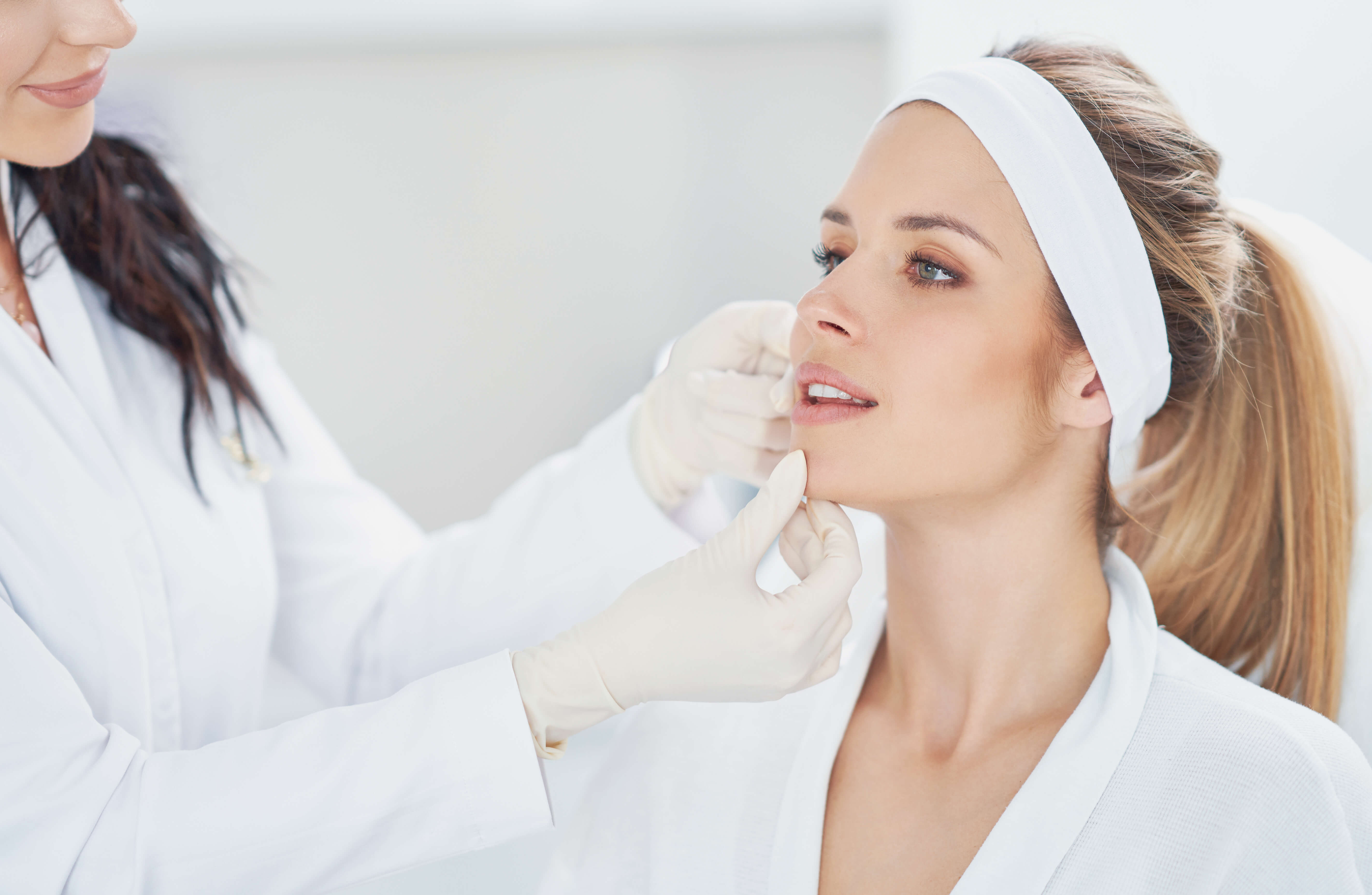 Woman receiving a cosmetic procedure from a professional in a clinical setting.