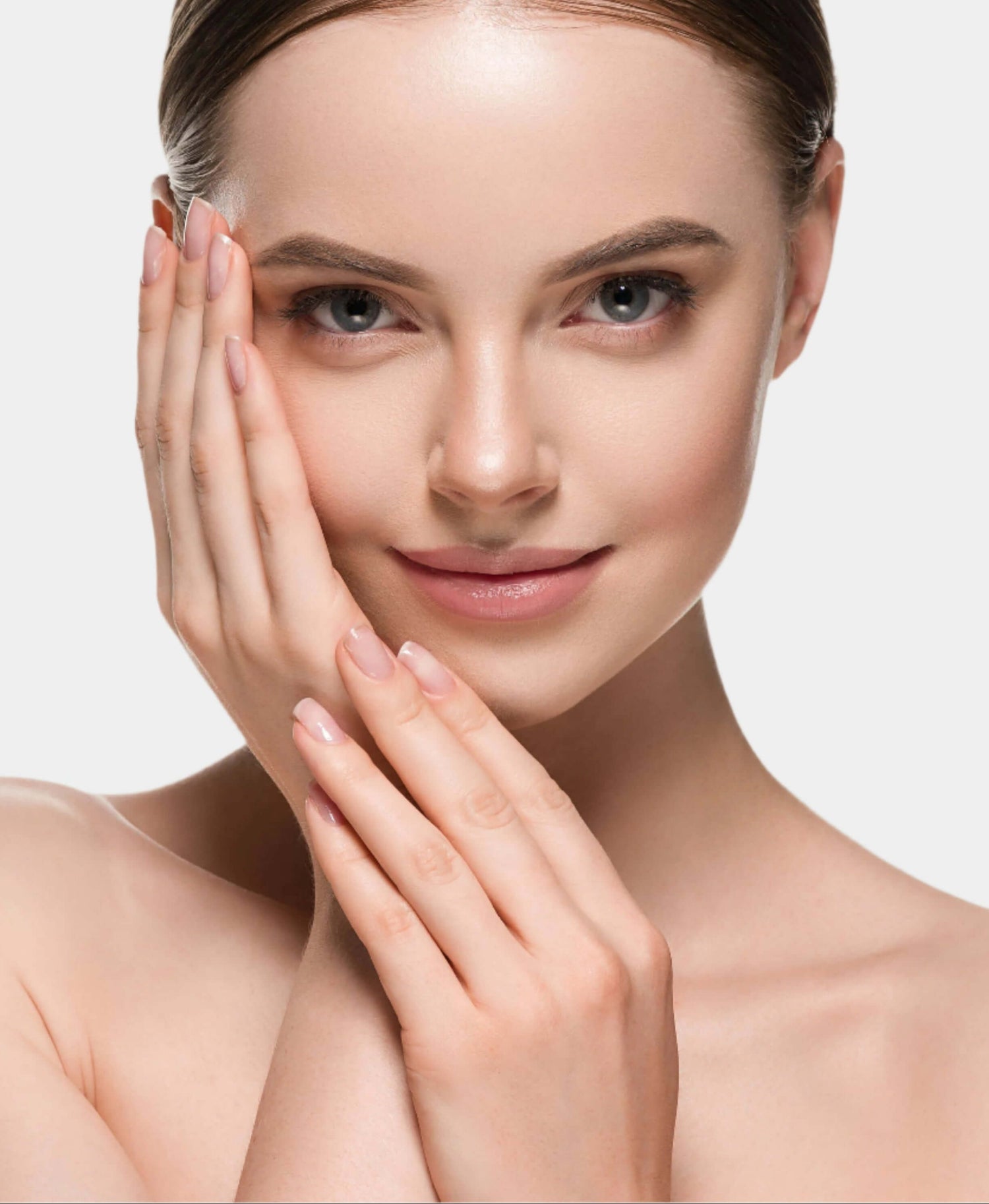 Woman with clear skin touching her face against a neutral background